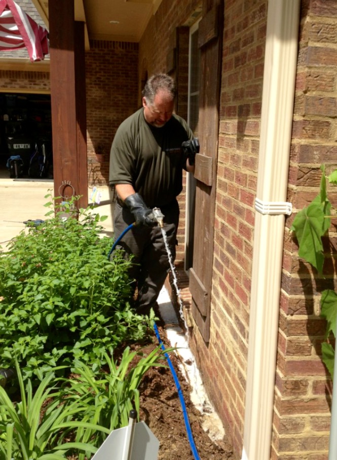 David McNeece applying termite treatment around the foundation of a Madison MS home